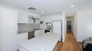 A modern kitchen with white cabinetry, a central island, and a microwave.