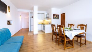 Um apartamento moderno com sala de jantar, cozinha e um sofá azul.