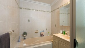 A bathroom with a bathtub, a sink, a mirror, and a towel rack.
