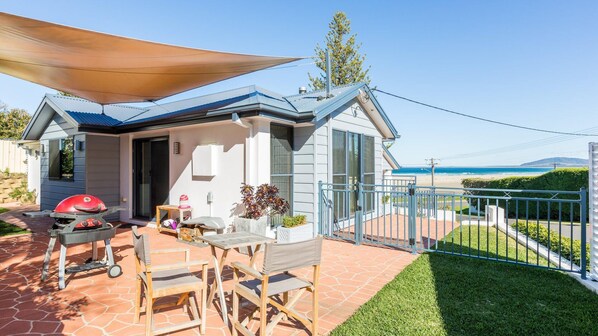 A coastal property with a patio, barbecue, and seating area.