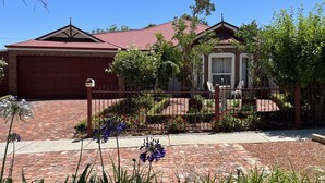 A house with a red brick garage, a red roof, and a brick pathway leading to the front door.