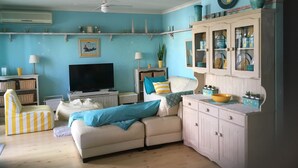 A living room with a sofa, television, and decorative items.