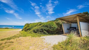 Une propriété située en bord de mer, dotée d’un espace extérieur couvert, d’une vue sur l’océan et d’un phare visible au loin.
