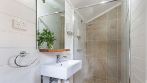 Ein modernes Badezimmer mit Waschbecken, Spiegel und einer Duschkabine.
