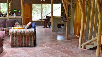 A spacious room with a high bamboo ceiling, a patterned rug, and a sofa with a blanket.