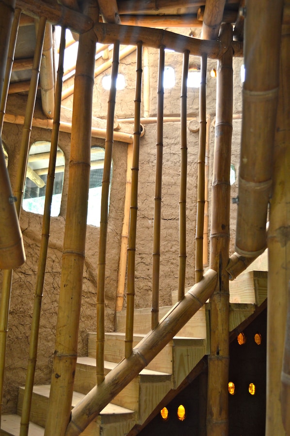 A bamboo staircase with a rustic interior design, wooden railings, and small windows allowing natural light.