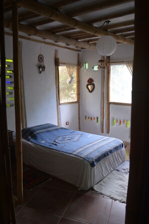 A room with a bed, bamboo ceiling, and decorative items on the walls.