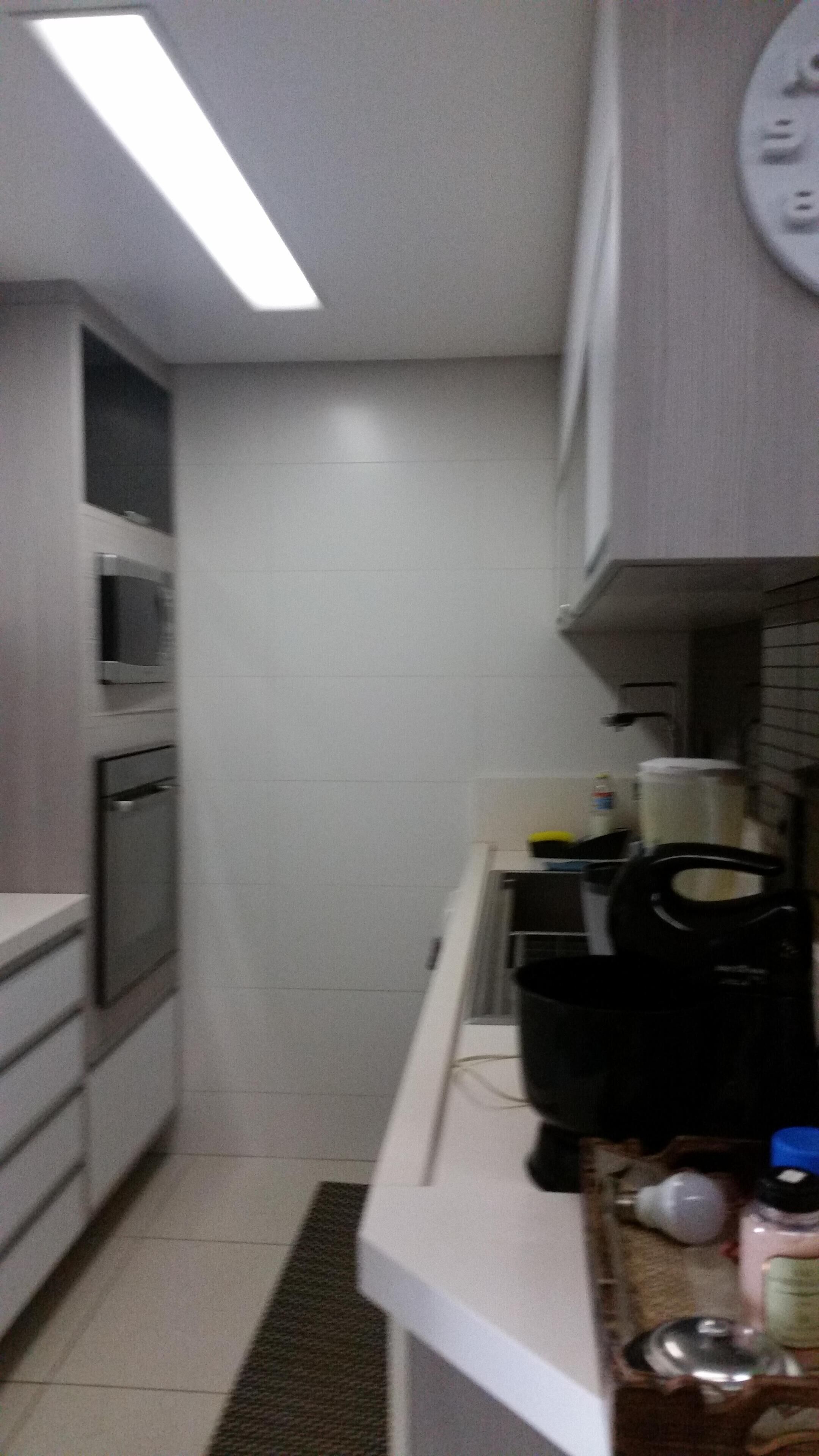 A narrow kitchen with white cabinets, a microwave, and a coffee maker on the counter.