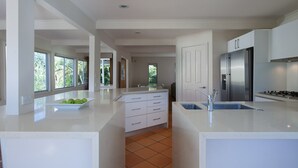 A modern kitchen with white cabinetry, a stainless steel refrigerator, and a large island with a sink.