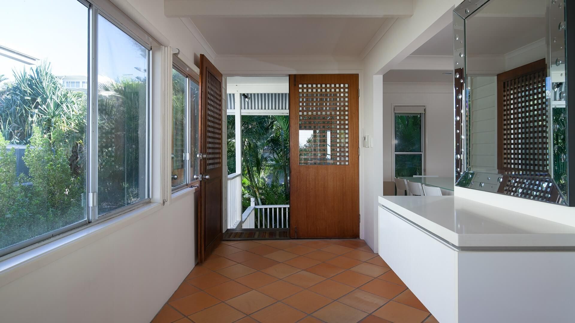 A narrow hallway with large windows, a wooden door, and a glass partition.