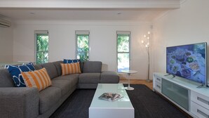 A modern living room with a grey sectional sofa, a coffee table, a TV, and a floor lamp.