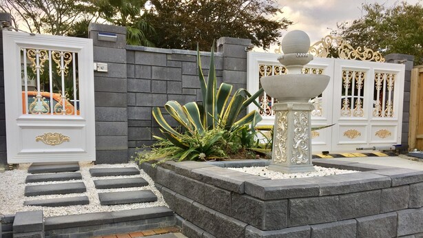 A gated entrance with a stone pathway leading to a wooden deck. - Amber Homes B Half Moon Bay (Bucklands Beach)