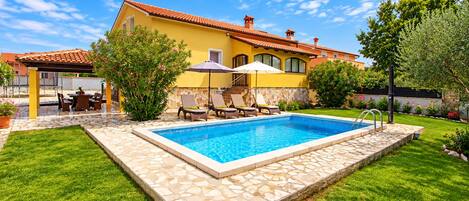 Um imóvel residencial com piscina, área de estar externa e um jardim bem cuidado.