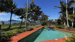 A swimming pool with a clear view of the ocean and mountains in the background.
