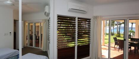 Une chambre d’hôtel avec deux lits, une porte-fenêtre coulissante donnant sur un balcon, un climatiseur et un ventilateur de plafond.