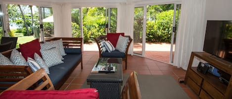 A living room with a sofa, chairs, a coffee table, and a television.