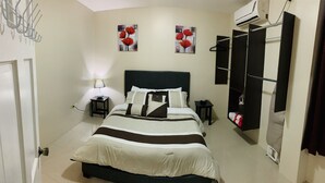 Une chambre à coucher avec un lit, des tables de chevet, une lampe, une armoire et deux tableaux accrochés au mur.