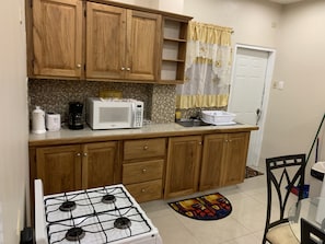Una cocina con armarios de madera, microondas, estufa y pileta.