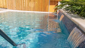 Une piscine entourée d’une clôture en bois et agrémentée d’une cascade.