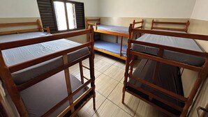 Ein Schlafsaalzimmer mit Etagenbetten, einem Fenster mit Rollläden und einer Klimaanlage an der Wand.