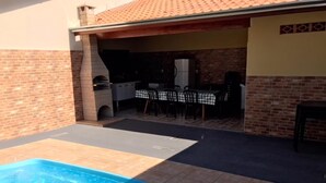 Ein Garten mit Pool, Grillplatz und Essbereich.