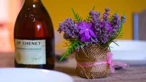 Een fles wijn en een klein bloemenmandje op een tafel.