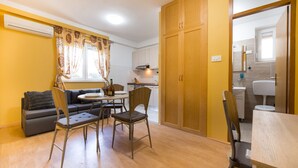 Een knus woongedeelte met een bank, eettafel, stoelen en een kitchenette.