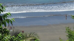 A beach with people walking and swimming. - Great second floor condo with pool view- Best location in Jaco beach (Jaco)