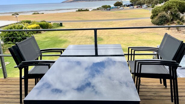 Una terraza con mesa y sillas que da a una playa y al océano.