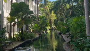 A serene waterway flanked by lush greenery and modern buildings, suggesting a tranquil resort setting. - Ground floor, Poolside Luxury Apartment (Palm Cove)