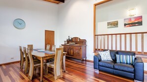 Un coin repas avec une table et des chaises en bois, un buffet en bois et un canapé bleu agrémenté de coussins à motifs.