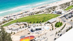 Luftaufnahme einer Küstenlandschaft mit Strand, Parkplatz und Skatepark.
