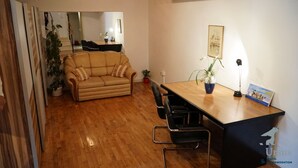Een woonkamer met een bank, een eettafel, stoelen en een potplant.