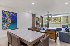 A modern living room with a marble table, sofas, and a large painting on the wall.