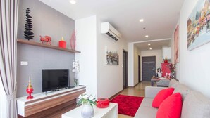 A modern living room with a flat-screen TV, a sofa with red cushions, a red rug, and a small white table with a vase. - Romantic Honeymoon Siam Suite, Central Chiang Mai (Tambon Chang Khlan)