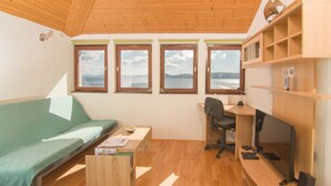 A compact room with a bed, a desk with a computer, and a TV. There are three windows offering a view of the sea. - Holiday House Botta With Pool (Seaside Near Split) (Marušici)