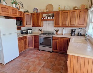 Eine Küche mit Holzausstattung, einem weißen Kühlschrank, einer Mikrowelle, einem Toaster, einem Herd und einem Spülbecken.