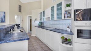 A kitchen with white cabinets, a blue countertop, and a built-in oven. - Sail Away - Aldinga Beach - C21 SouthCoast Holidays (Aldinga Beach)