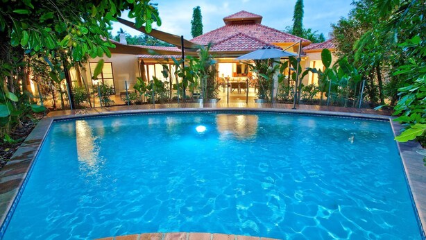 A swimming pool surrounded by lush greenery and a building with a tiled roof. - 7 Solander Boulevard, Port Douglas QLD 4877 (Port Douglas)