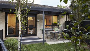 Una casa moderna con un porche cubierto, comedor y un interior visible con sofá y mesa.