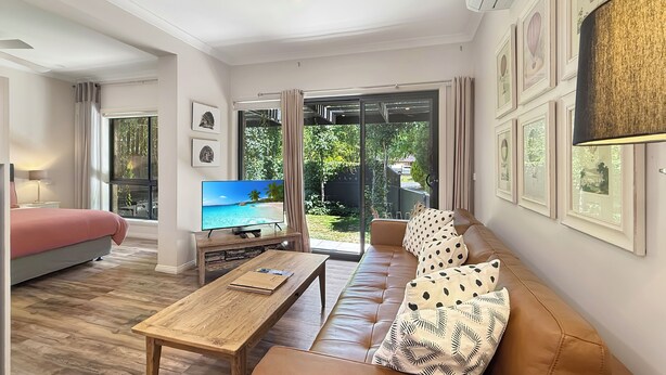 Una sala moderna con un sofá, una mesa de centro y un televisor que muestra una escena de playa.