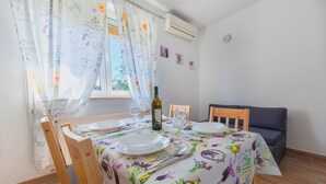 A dining area with a table set for two, featuring a floral tablecloth, a bottle of wine, and a glass. - Apartment Raspolic - no.1 (Trinajstici)