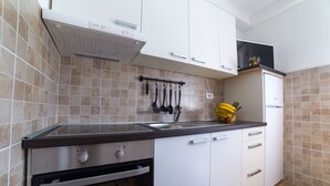A kitchen with white cabinets, a stainless steel oven, a black countertop, and a tiled backsplash. - Apartment Raspolic - no.1 (Trinajstici)