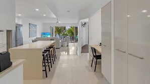 A modern kitchen with a central island, dining area with chairs, and a view of the outdoors. - Rojo at Island Views—A Breezy Beachfront Retreat (Palm Cove)