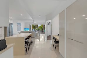 A modern kitchen with a central island, dining area with chairs, and a view of the outdoors.