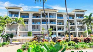 A multi-story hotel with balconies, palm trees, and a well-maintained garden. - Rojo at Island Views—A Breezy Beachfront Retreat (Palm Cove)