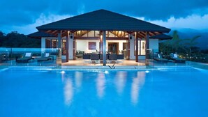 A modern resort with a pool, lounge area, and a covered seating area.