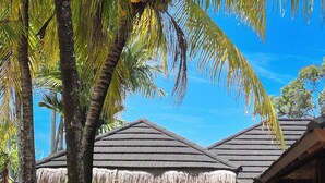 A tropical resort with thatched-roof huts, lush greenery, and a clear blue sky.