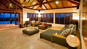 A spacious living area with a high ceiling, built-in bookshelves, and a large window overlooking a scenic view.