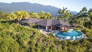 A modern resort with multiple buildings, a swimming pool, and lush greenery.